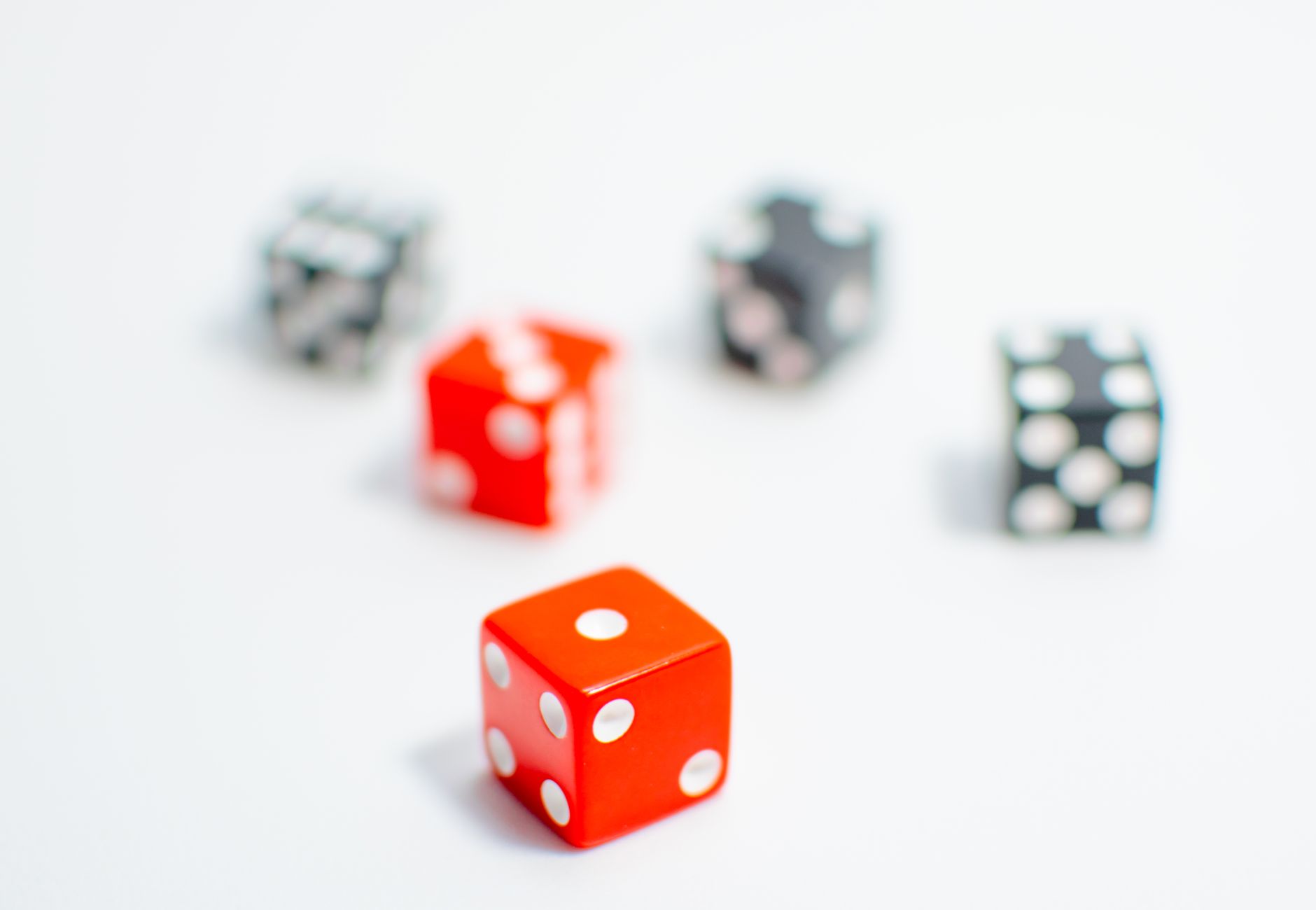 Vibrant red and black dice with white pips on a minimalist white surface, emphasizing focus.